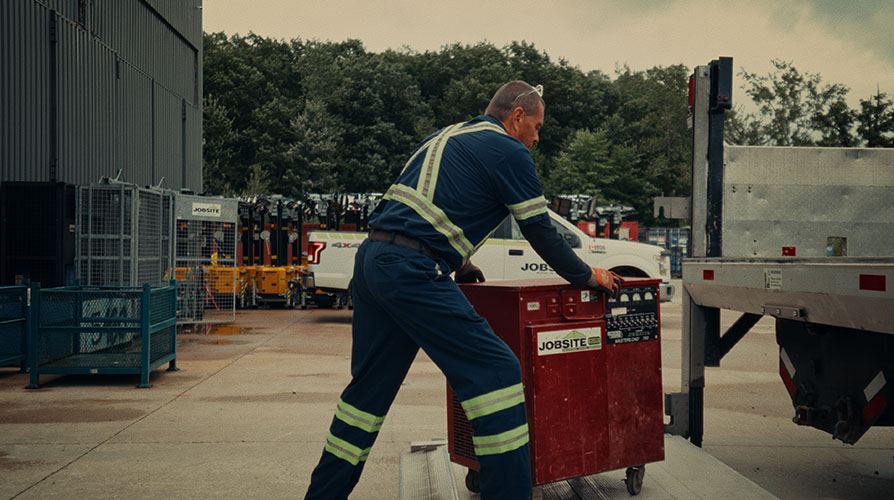 Employee loading jobsite equipment onto vehicle